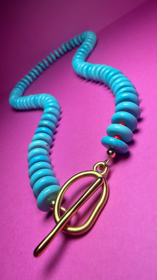 A turquoise spiral coiled cord necklace with a gold toggle clasp