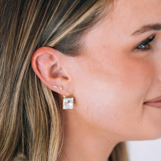 gold hoop earring with a square clear gemstone drop