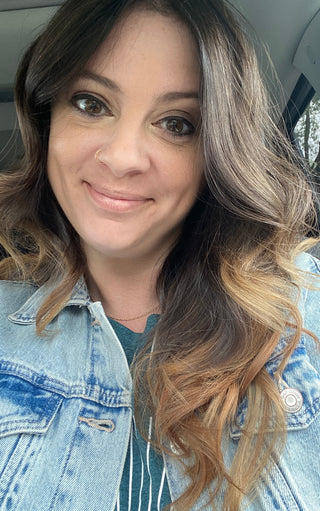 Woman with ombre hair wearing a denim jacket inside a vehicle.