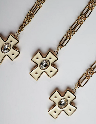gold-toned chain necklaces with cross-shaped pendants featuring cream enamel inlays and clear faceted gemstones
